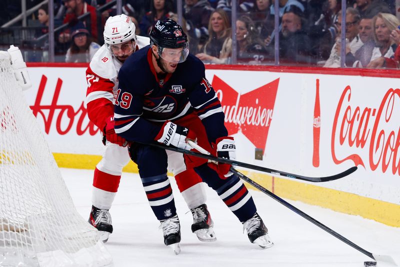 Jan 24, 2026; Winnipeg, Manitoba, CAN; Winnipeg Jets forward Jonathan Toews (19) tries to skate away from Detroit Red Wings forward Dylan Larkin (71) during the first period at Canada Life Centre. Mandatory Credit: Terrence Lee-Imagn Images