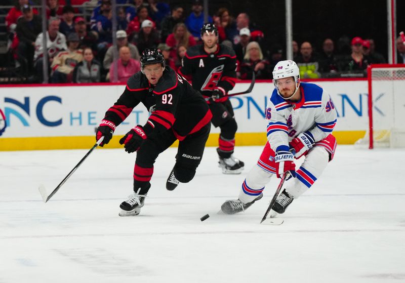 Mar 12, 2024; Raleigh, North Carolina, USA; Carolina Hurricanes center Evgeny Kuznetsov (92) and New York Rangers center Jack Roslovic (96) battle over the puck during the third period at PNC Arena. Mandatory Credit: James Guillory-USA TODAY Sports