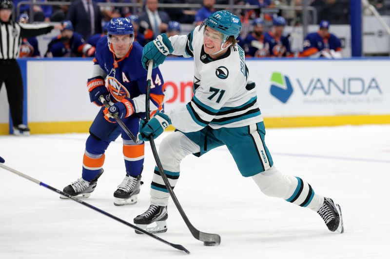 Oct 21, 2025; Elmont, New York, USA; San Jose Sharks center Macklin Celebrini (71) takes a shot against New York Islanders center Bo Horvat (14) during the first period at UBS Arena. Mandatory Credit: Brad Penner-Imagn Images