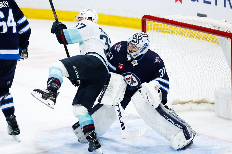 Apr 16, 2024; Winnipeg, Manitoba, CAN;  Seattle Kraken forward Yanni Gourde (37) runs into Winnipeg Jets goalie Connor Hellebuyck (37) during the third period at Canada Life Centre. Mandatory Credit: Terrence Lee-USA TODAY Sports