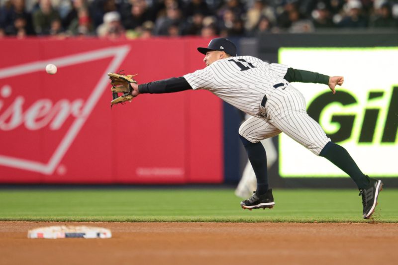 Apr 25, 2024; Bronx, New York, USA; New York Yankees shortstop Anthony Volpe (11) catches the ball for an out against the Oakland Athletics during the seventh inning at Yankee Stadium. Mandatory Credit: Vincent Carchietta-USA TODAY Sports