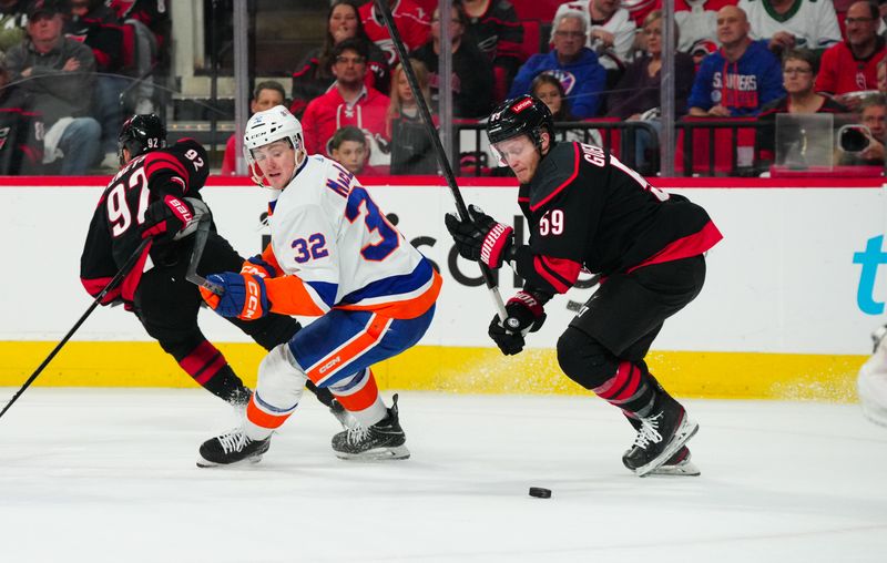 Apr 30, 2024; Raleigh, North Carolina, USA; Carolina Hurricanes center Jake Guentzel (59) takes the puck away from New York Islanders center Kyle MacLean (32) during the first period in game five of the first round of the 2024 Stanley Cup Playoffs at PNC Arena. Mandatory Credit: James Guillory-USA TODAY Sports