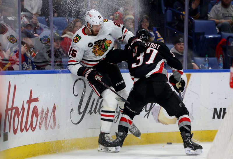 Jan 18, 2024; Buffalo, New York, USA;  Buffalo Sabres center Casey Mittelstadt (37) checks Chicago Blackhawks defenseman Jarred Tinordi (25) as he goes for a loose puck along the boards during the second period at KeyBank Center. Mandatory Credit: Timothy T. Ludwig-USA TODAY Sports