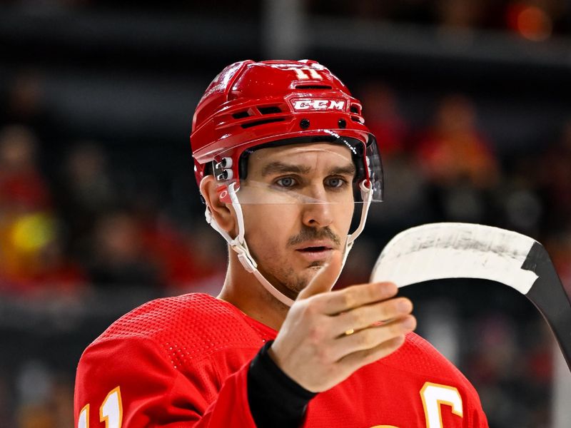 Jan 16, 2024; Calgary, Alberta, CAN; Calgary Flames center Mikael Backlund (11) checks his stick before the start of the first period against the Arizona Coyotes at Scotiabank Saddledome. Mandatory Credit: Brett Holmes-USA TODAY Sports