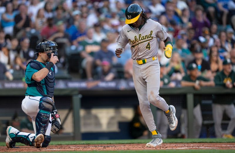 May 11, 2024; Seattle, Washington, USA; Oakland Athletics right fielder Lawrence Butler (4) scores a run in front of Seattle Mariners catcher Cal Raleigh (29) during the third inning at T-Mobile Park. Mandatory Credit: Stephen Brashear-USA TODAY Sports