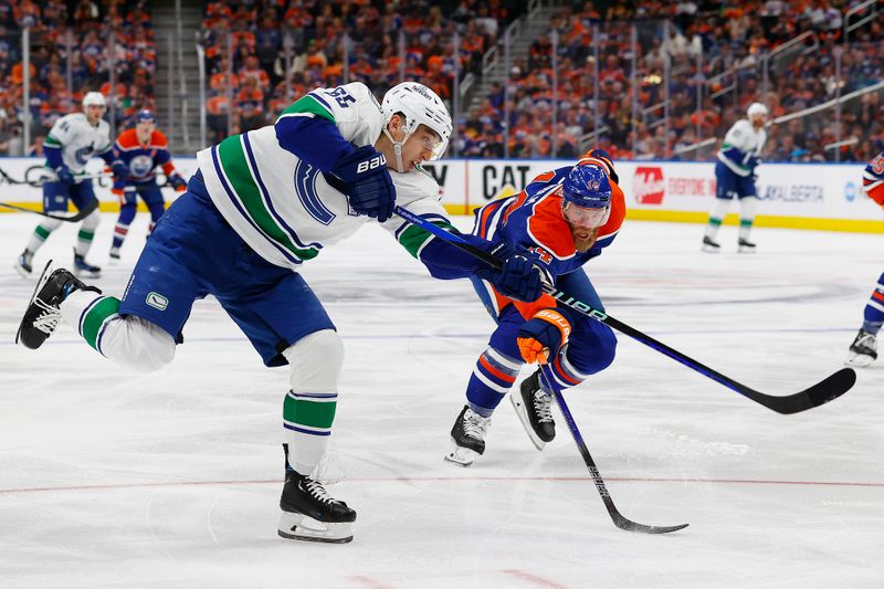 May 12, 2024; Edmonton, Alberta, CAN;Vancouver Canucks forward Ilya Mikheyev (65) gets a shot away in front of Edmonton Oilers defensemen Mattias Ekholm (14) during the second period in game three of the second round of the 2024 Stanley Cup Playoffs at Rogers Place. Mandatory Credit: Perry Nelson-USA TODAY Sports