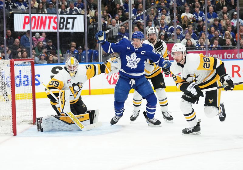 Apr 8, 2024; Toronto, Ontario, CAN; Toronto Maple Leafs center John Tavares (91) battles with Pittsburgh Penguins defenseman Erik Karlsson (65) in front of goaltender Alex Nedeljkovic (39) during the first period at Scotiabank Arena. Mandatory Credit: Nick Turchiaro-USA TODAY Sports