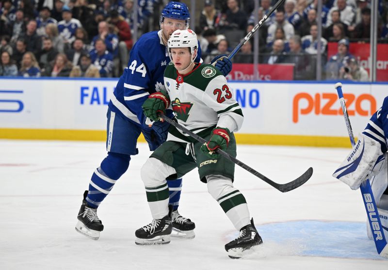 Jan 29, 2025; Toronto, Ontario, CAN;  Minnesota Wild forward Marco Rossi (23) battles for position against Toronto Maple Leafs defenseman Morgan Rielly (44) in the second period at Scotiabank Arena. Mandatory Credit: Dan Hamilton-Imagn Images