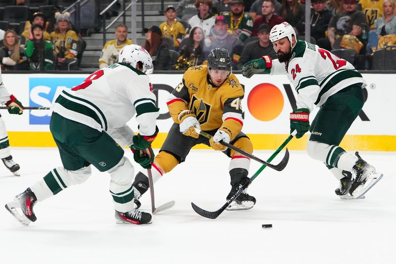 Apr 22, 2025; Las Vegas, Nevada, USA; Vegas Golden Knights center Ivan Barbashev (49) loses the puck between Minnesota Wild defenseman Zeev Buium (8) and Minnesota Wild defenseman Zach Bogosian (24) during the second period of game two of the first round of the 2025 Stanley Cup Playoffs at T-Mobile Arena. Mandatory Credit: Stephen R. Sylvanie-Imagn Images
