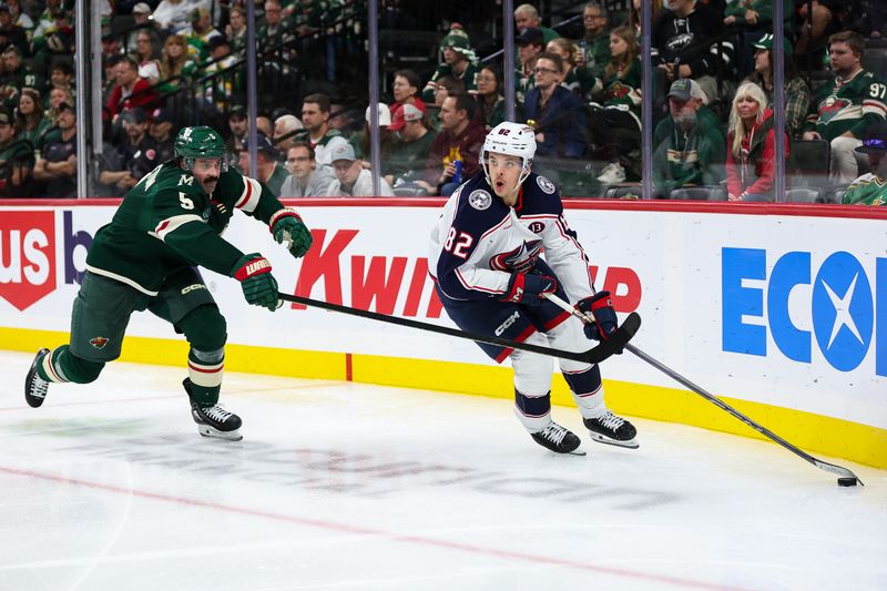 Oct 10, 2024; Saint Paul, Minnesota, USA; Columbus Blue Jackets left wing Mikael Pyyhtia (82) skates with the puck as Minnesota Wild defenseman Jake Middleton (5) defends during the third period at Xcel Energy Center. Mandatory Credit: Matt Krohn-Imagn Images