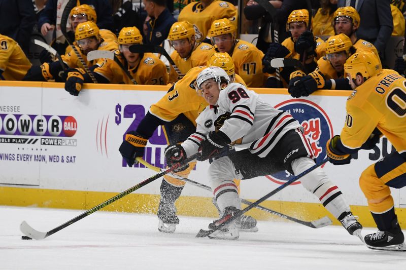 Jan 2, 2024; Nashville, Tennessee, USA; Chicago Blackhawks center Connor Bedard (98) passes the puck as he is defended by Nashville Predators defenseman Jeremy Lauzon (3) during the third period at Bridgestone Arena. Mandatory Credit: Christopher Hanewinckel-USA TODAY Sports