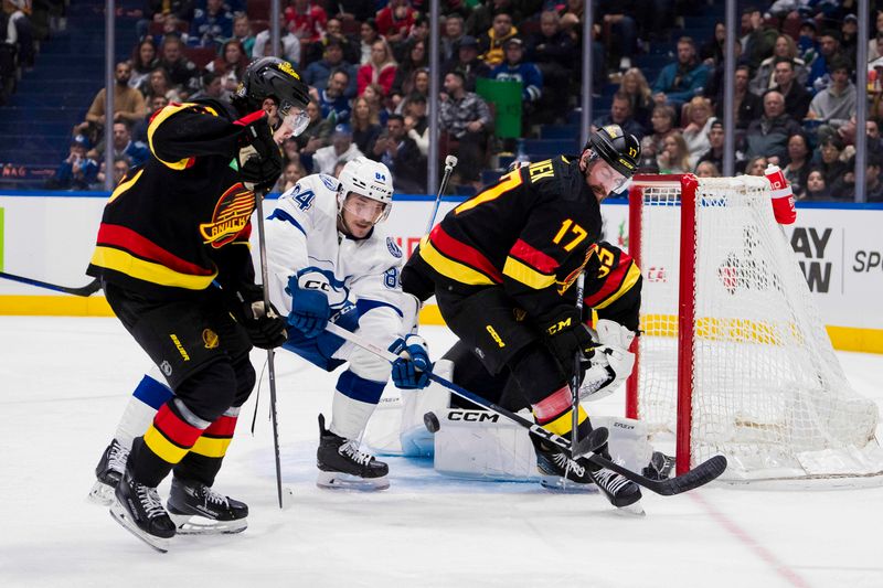 Dec 12, 2023; Vancouver, British Columbia, CAN; Vancouver Canucks defenseman Quinn Hughes (43) and defenseman Filip Hronek (17) battle with Tampa Bay Lightning forward Tanner Jeannot (84) in the third period at Rogers Arena. Vancouver won 4-1. Mandatory Credit: Bob Frid-USA TODAY Sports