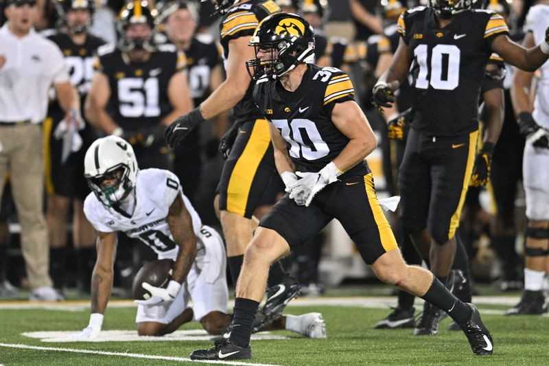 Sep 30, 2023; Iowa City, Iowa, USA; Iowa Hawkeyes defensive back Quinn Schulte (30) reacts after tackling Michigan State Spartans wide receiver Alante Brown (0) during the third quarter at Kinnick Stadium. Mandatory Credit: Jeffrey Becker-USA TODAY Sports