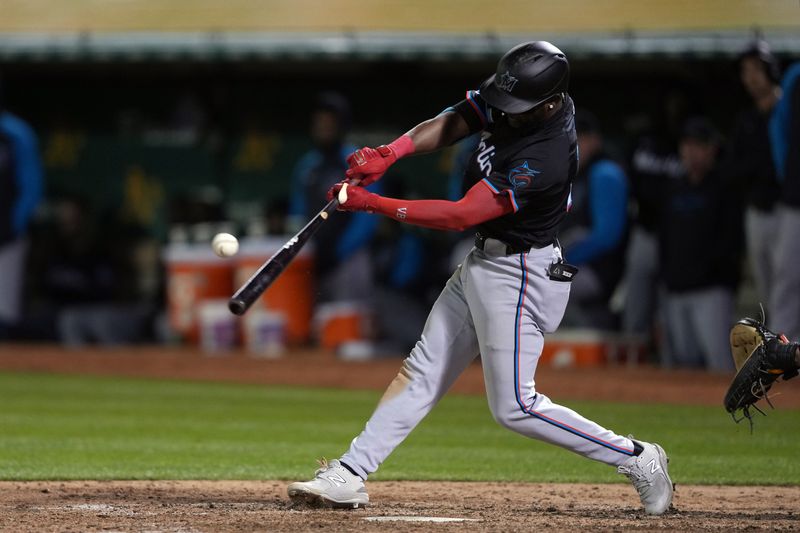 May 3, 2024; Oakland, California, USA; Miami Marlins third baseman Vidal Brujan (17) hits an RBI double against the Oakland Athletics during the ninth inning at Oakland-Alameda County Coliseum. Mandatory Credit: Darren Yamashita-USA TODAY Sports