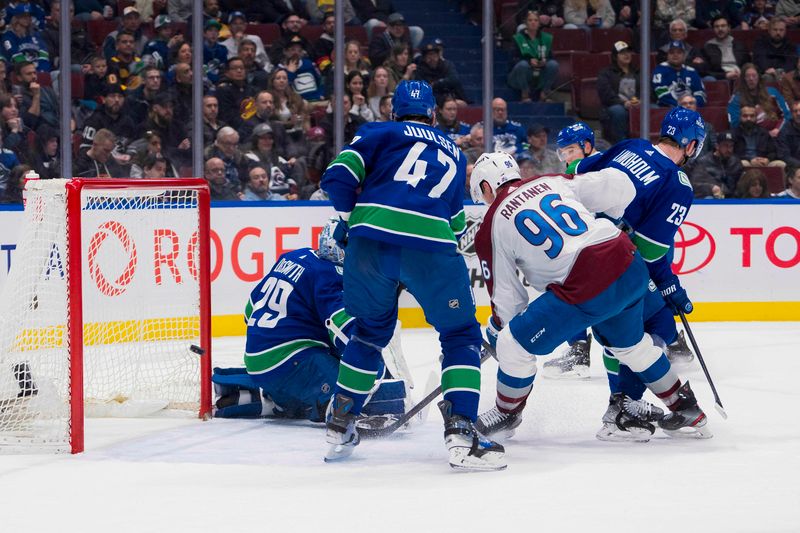 Mar 13, 2024; Vancouver, British Columbia, CAN; Vancouver Canucks forward Elias Lindholm (23) and defenseman Noah Juulsen (47) watch as Colorado Avalanche forward Mikko Rantanen (96) scores on goalie Casey DeSmith (29) in the second period at Rogers Arena. Mandatory Credit: Bob Frid-USA TODAY Sports