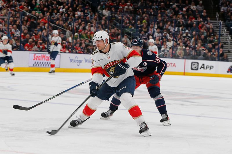 Mar 20, 2025; Columbus, Ohio, USA; Florida Panthers center Sam Reinhart (13) passes the puck asColumbus Blue Jackets right wing Yegor Chinakhov (59) trails the play during the third period at Nationwide Arena. Mandatory Credit: Russell LaBounty-Imagn Images