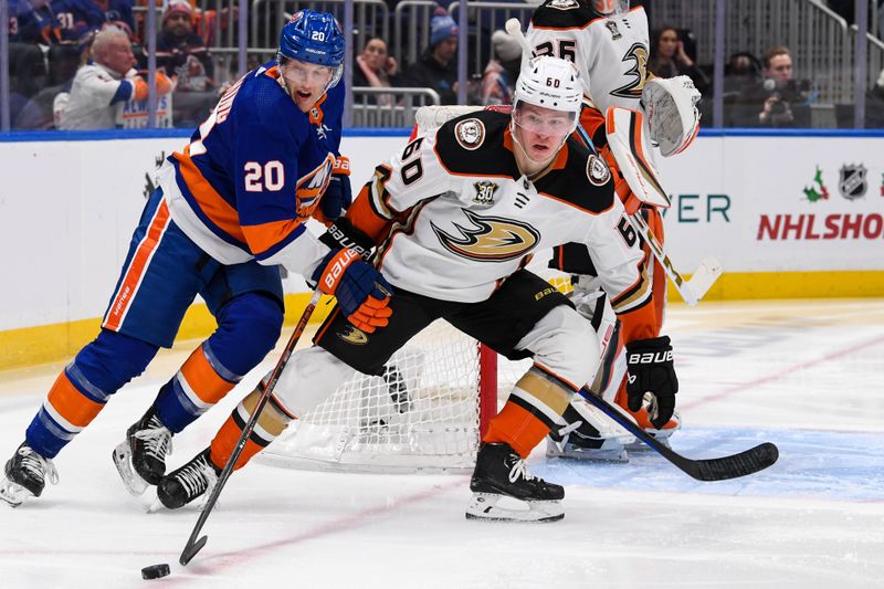 Dec 13, 2023; Elmont, New York, USA; Anaheim Ducks defenseman Jackson LaCombe (60) skates the puck from behind the net chased by New York Islanders right wing Hudson Fasching (20) during the second period at UBS Arena. Mandatory Credit: Dennis Schneidler-USA TODAY Sports