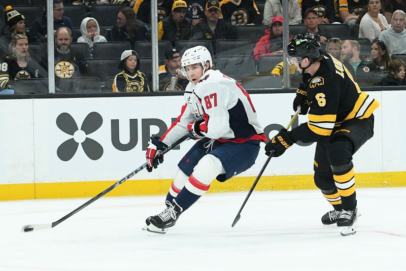 Sep 21, 2025; Boston, Massachusetts, USA;  Washington Capitals forward Bogdan Trineyev (87) controls the puck past Boston Bruins defenseman Mason Lohrei (6) during the second period at TD Garden. Mandatory Credit: Bob DeChiara-Imagn Images
