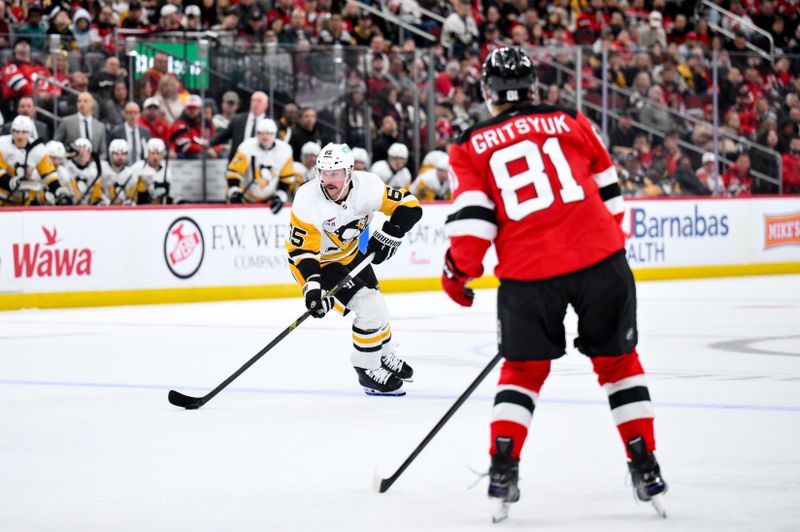 Nov 8, 2025; Newark, New Jersey, USA; Pittsburgh Penguins defenseman Erik Karlsson (65) skates with the puck while defended by New Jersey Devils right wing Arseny Gritsyuk (81) during the third period at Prudential Center. Mandatory Credit: John Jones-Imagn Images