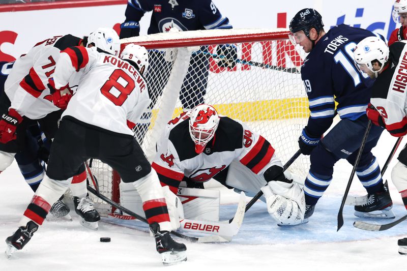 Jan 11, 2026; Winnipeg, Manitoba, CAN; New Jersey Devils defenceman Jonathan Kovacevic (8) and Winnipeg Jets center Jonathan Toews (19) scramble for the puck in front of New Jersey Devils goaltender Jake Allen (34) in the third period at Canada Life Centre. Mandatory Credit: James Carey Lauder-Imagn Images