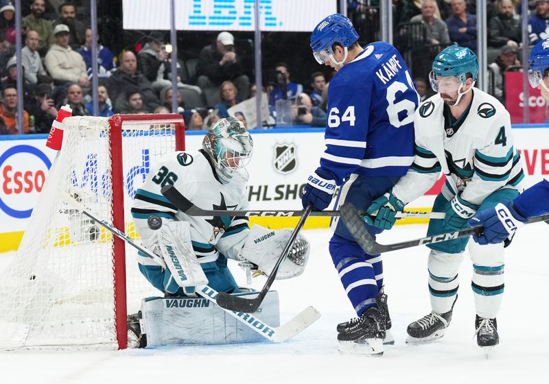 Jan 9, 2024; Toronto, Ontario, CAN; Toronto Maple Leafs center David Kampf (64) battles for the puck with San Jose Sharks defenseman Kyle Burroughs (4) in front of goaltender Kaapo Kahkonen (36) during the first period at Scotiabank Arena. Mandatory Credit: Nick Turchiaro-USA TODAY Sports