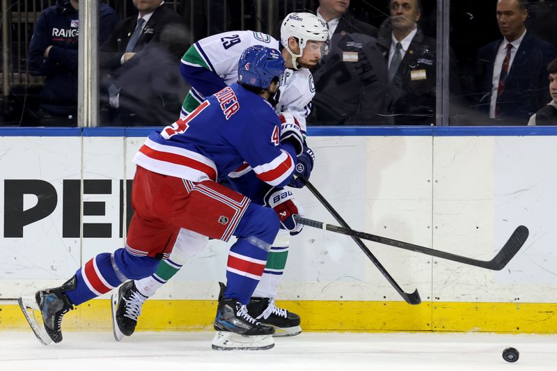 Dec 16, 2025; New York, New York, USA; Vancouver Canucks defenseman Marcus Pettersson (29) plays the puck against New York Rangers defenseman Braden Schneider (4) during the first period at Madison Square Garden. Mandatory Credit: Brad Penner-Imagn Images