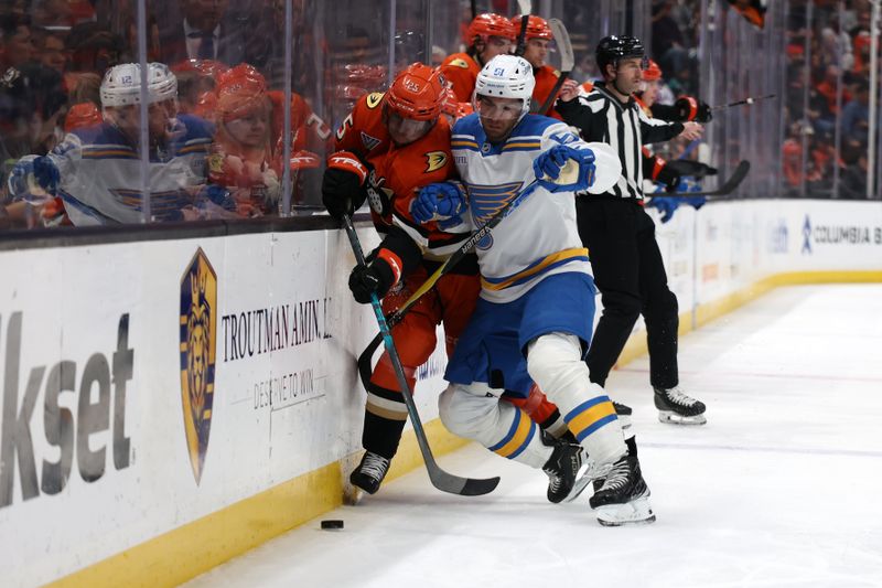 Mar 8, 2026; Anaheim, California, USA;  St. Louis Blues defenseman Matthew Kessel (51) checks Anaheim Ducks center Ryan Poehling (25) into the boards during the second period at Honda Center. Mandatory Credit: Kiyoshi Mio-Imagn Images