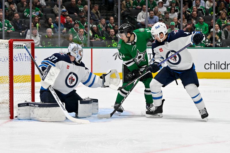 Feb 29, 2024; Dallas, Texas, USA; Winnipeg Jets goaltender Connor Hellebuyck (37) and defenseman Neal Pionk (4) and Dallas Stars center Logan Stankoven (11) look for the puck in the Jets zone during the second period at the American Airlines Center. Mandatory Credit: Jerome Miron-USA TODAY Sports