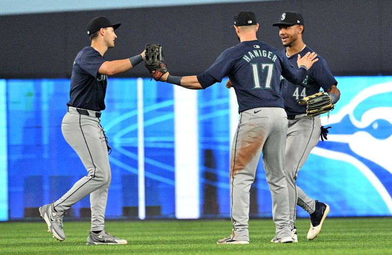 Apr 10, 2024; Toronto, Ontario, CAN;  Seattle Mariners left fielder Dominic Canzone (8) and center fielder Julio Rodriguez (44) and right fielder Mitch Haniger (17) celebrate after a win over the Toronto Blue Jays at Rogers Centre. Mandatory Credit: Dan Hamilton-USA TODAY Sports