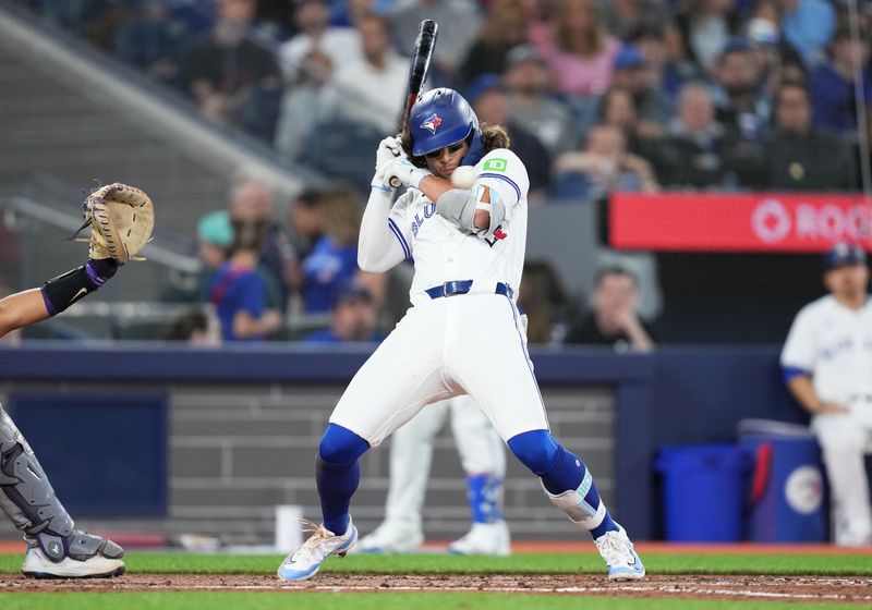 Apr 12, 2024; Toronto, Ontario, CAN; Toronto Blue Jays shortstop Bo Bichette (11) gets a inside pitch against the Colorado Rockies during the fifth inning at Rogers Centre. Mandatory Credit: Nick Turchiaro-USA TODAY Sports