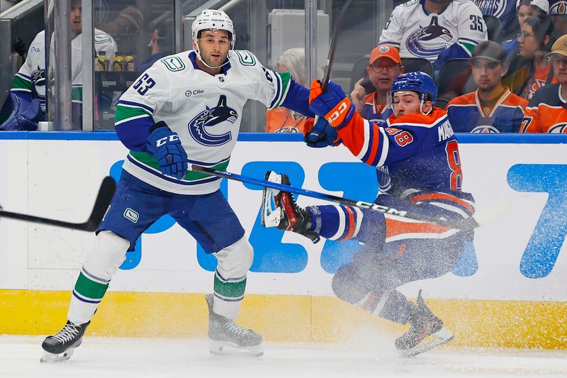 Sep 28, 2025; Edmonton, Alberta, CAN; Vancouver Canucks forward Max Sasson (63) checks Edmonton Oilers forward Andrew Mangiapane (88) during the first period at Rogers Place. Mandatory Credit: Perry Nelson-Imagn Images