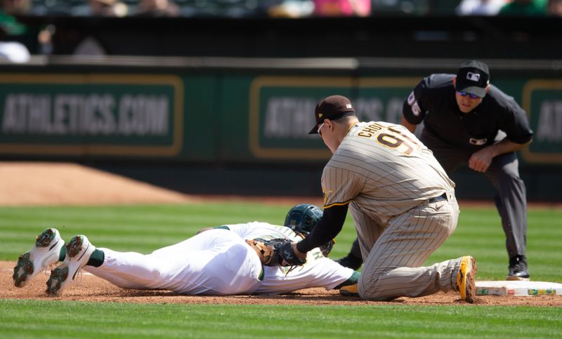 Sep 16, 2023; Oakland, California, USA; San Diego Padres first baseman Ji Man Choi (91) tags out Oakland Athletics center fielder Lawrence Butler (22) on a pickoff play during the second inning at Oakland-Alameda County Coliseum. Umpire is Alex McKay. Mandatory Credit: D. Ross Cameron-USA TODAY Sports