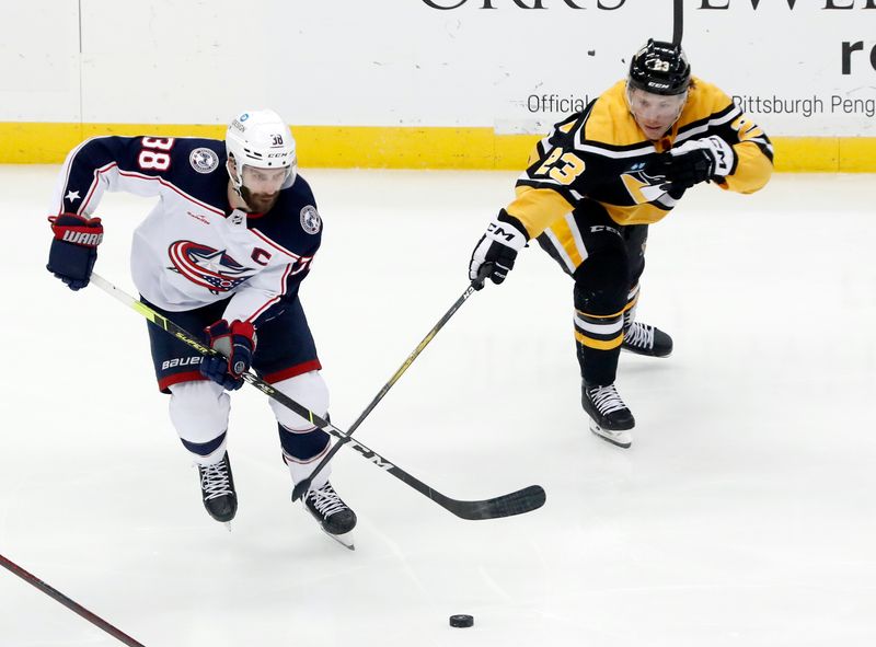 Dec 6, 2022; Pittsburgh, Pennsylvania, USA; Columbus Blue Jackets center Boone Jenner (38) moves the puck  against Pittsburgh Penguins left wing Brock McGinn (23) during the second period at PPG Paints Arena. Mandatory Credit: Charles LeClaire-USA TODAY Sports