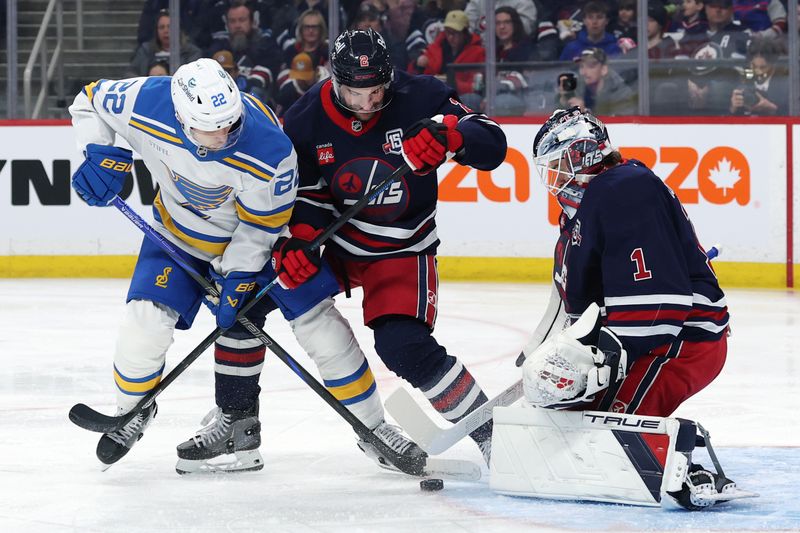 Mar 15, 2026; Winnipeg, Manitoba, CAN; St. Louis Blues center Pius Suter (22) and Winnipeg Jets defenseman Dylan DeMelo (2) dig for a rebound in front of Winnipeg Jets goaltender Eric Comrie (1) in the second period at Canada Life Centre. Mandatory Credit: James Carey Lauder-Imagn Images