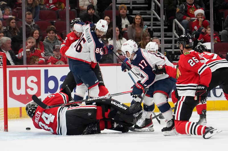 Dec 1, 2024; Chicago, Illinois, USA; Chicago Blackhawks goaltender Petr Mrazek (34) makes a save on Columbus Blue Jackets right wing Justin Danforth (17) during the second period at United Center. Mandatory Credit: David Banks-Imagn Images