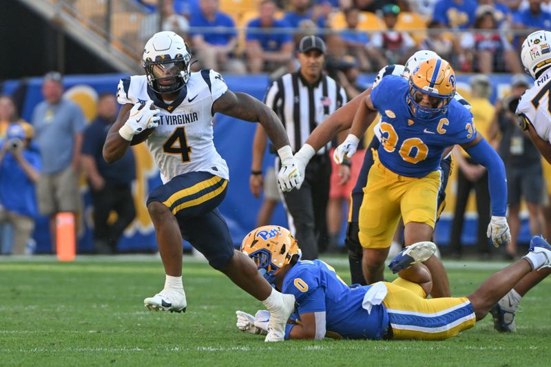 Sep 14, 2024; Pittsburgh, Pennsylvania, USA; West Virginia Mountaineers running back CJ Donaldson Jr. (4) breaks a tackle attempt by Pittsburgh Panthers linebacker Braylon Lovelace (on ground) in the second quarter at Acrisure Stadium. Mandatory Credit: Barry Reeger-Image Images