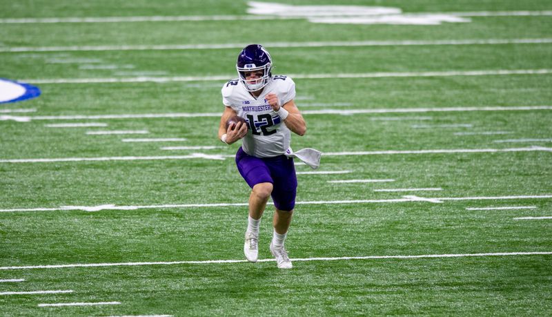 Dec 19, 2020; Indianapolis, Indiana, USA; Northwestern Wildcats quarterback Peyton Ramsey (12) runs the ball against the Ohio State Buckeyes during the first half of the Big Ten Championship game at Lucas Oil Stadium. Mandatory Credit: Doug McSchooler-USA TODAY Sports