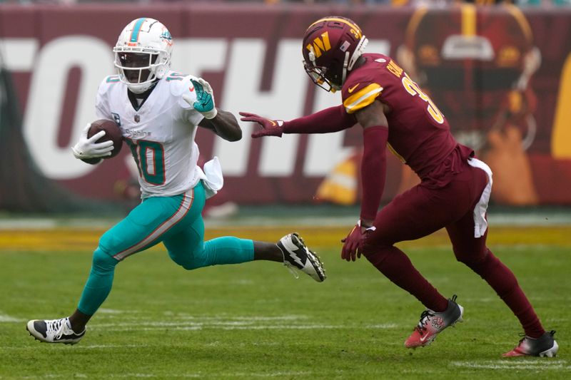 Miami Dolphins wide receiver Tyreek Hill (10) runs past Washington Commanders safety Kamren Curl (31) during an NFL football game Sunday, Dec. 3, 2023, in Landover, Md. (AP Photo/Mark Schiefelbein)