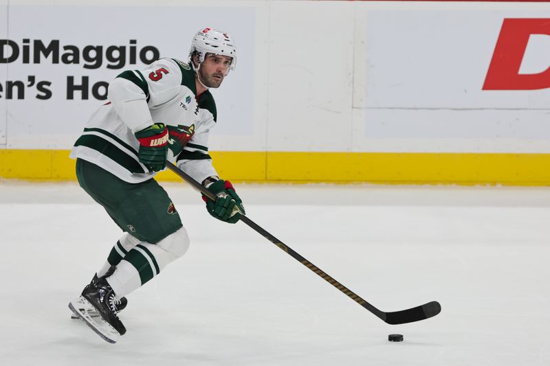 Oct 22, 2024; Sunrise, Florida, USA;  Minnesota Wild defenseman Jake Middleton (5) moves the puck against the Florida Panthers during the third period at Amerant Bank Arena. Mandatory Credit: Sam Navarro-Imagn Images