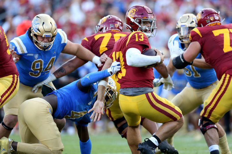 Nov 18, 2023; Los Angeles, California, USA; USC Trojans quarterback Caleb Williams (13) scrambles against UCLA Bruins defensive lineman Carl Jones Jr. (4) during the second quarter at United Airlines Field at Los Angeles Memorial Coliseum. Mandatory Credit: Jason Parkhurst-USA TODAY Sports