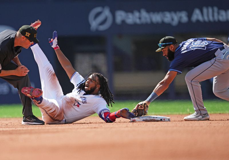 May 18, 2024; Toronto, Ontario, CAN; Toronto Blue Jays first base Vladimir Guerrero Jr. (27) is safe at second base ahead of the tag from Tampa Bay Rays second baseman Amed Rosario (10) after hitting a double during the fourth inning at Rogers Centre. Mandatory Credit: Nick Turchiaro-USA TODAY Sports