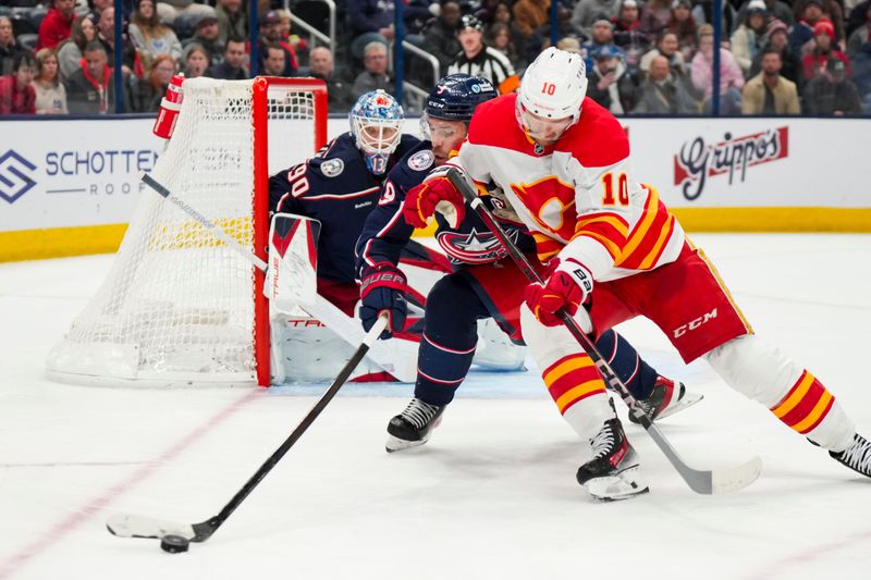 Nov 29, 2024; Columbus, Ohio, USA;  Calgary Flames center Jonathan Huberdeau (10) skates for the puck against Columbus Blue Jackets defenseman Ivan Provorov (9) in the third period at Nationwide Arena. Mandatory Credit: Aaron Doster-Imagn Images