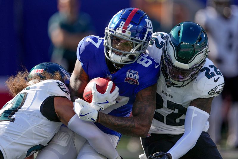 New York Giants wide receiver Ihmir Smith-Marsette (87) is tackled by Philadelphia Eagles safety Sydney Brown (21) and cornerback Kelee Ringo (22) during the third quarter of an NFL football game, Sunday, Oct. 20, 2024, in East Rutherford, N.J. (AP Photo/Seth Wenig)