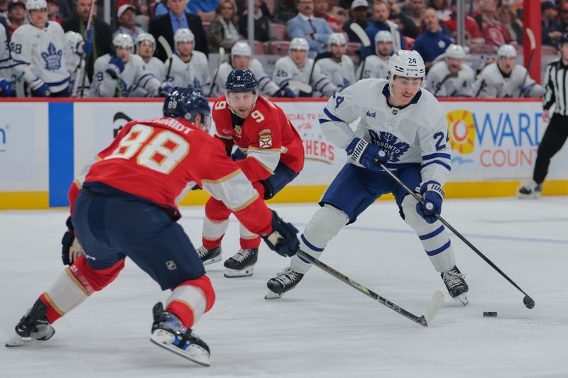 Nov 27, 2024; Sunrise, Florida, USA; Toronto Maple Leafs center Connor Dewar (24) moves the puck against the Florida Panthers during the second period at Amerant Bank Arena. Mandatory Credit: Sam Navarro-Imagn Images