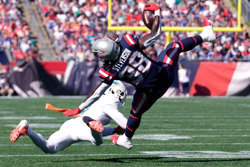 New England Patriots running back Rhamondre Stevenson (38) hangs onto the ball after colliding with Miami Dolphins cornerback Kader Kohou (4) during the first half of an NFL football game, Sunday, Oct. 6, 2024, in Foxborough, Mass. (AP Photo/Steven Senne)