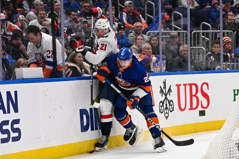 Dec 29, 2023; Elmont, New York, USA; New York Islanders defenseman Alexander Romanov (28) checks Washington Capitals center Aliaksei Protas (21) into the boards during the third period at UBS Arena. Mandatory Credit: Dennis Schneidler-USA TODAY Sports