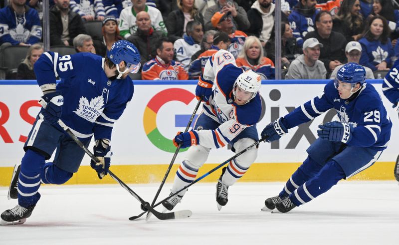 Nov 16, 2024; Toronto, Ontario, CAN;  Toronto Maple Leafs defenseman Oliver Ekman-Larsson (95) and forward Pontus Holmberg (29) combine to break up a rush by Edmonton Oilers forward Connor McDavid (97) in the second period at Scotiabank Arena. Mandatory Credit: Dan Hamilton-Imagn Images