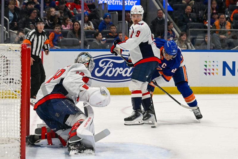 Nov 30, 2025; Elmont, New York, USA;  Washington Capitals right wing Ryan Leonard (9) defends against New York Islanders left wing Anders Lee (27) during the second period at UBS Arena. Mandatory Credit: Dennis Schneidler-Imagn Images