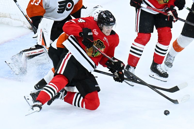 Dec 23, 2025; Chicago, Illinois, USA;  Chicago Blackhawks center Colton Dach (34) fight for the puck with Philadelphia Flyers defenseman Emil Andrae (36) during the third period at United Center. Mandatory Credit: Matt Marton-Imagn Images