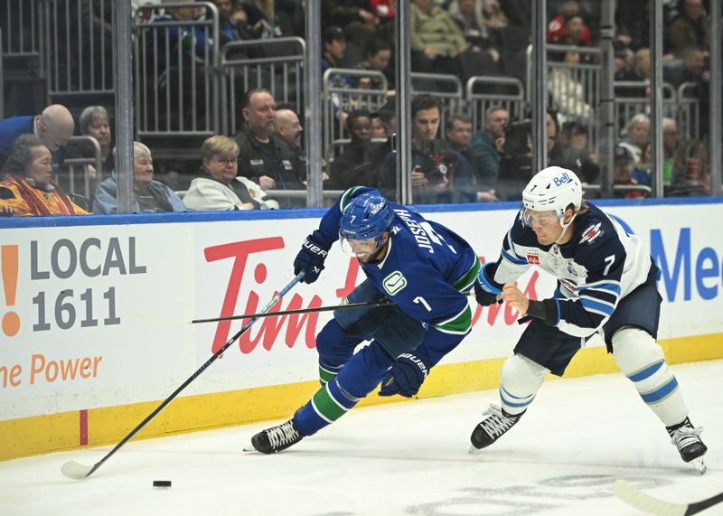 Feb 25, 2026; Vancouver, British Columbia, CAN;Vancouver Canucks defenseman Pierre-Olivier Joseph (7)  skates with the puck against Winnipeg Jets center Vladislav Namestnikov (7) during the first period at Rogers Arena. Mandatory Credit: Simon Fearn-Imagn Images